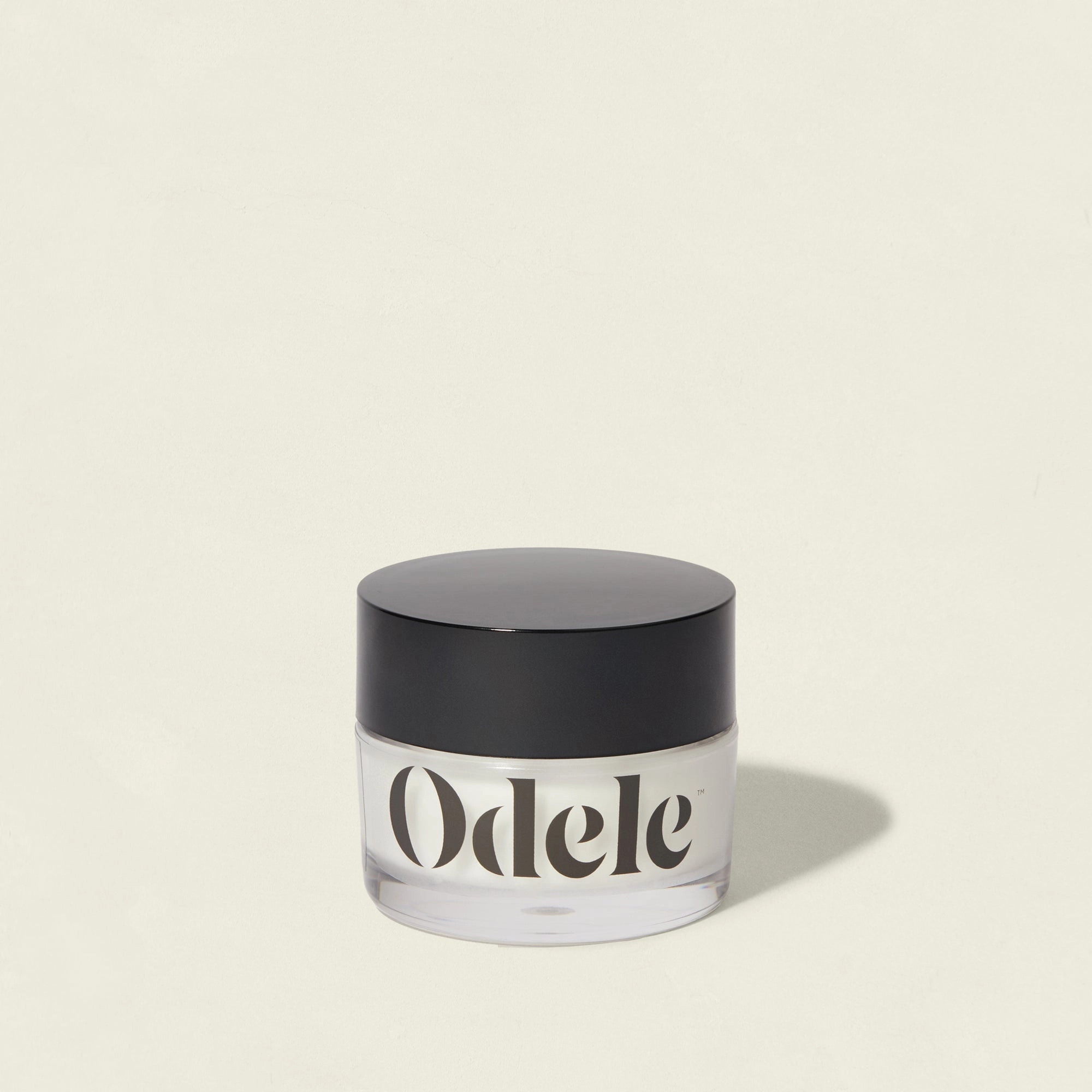 A clear jar of Odele Cream Pomade with a black lid on a light background