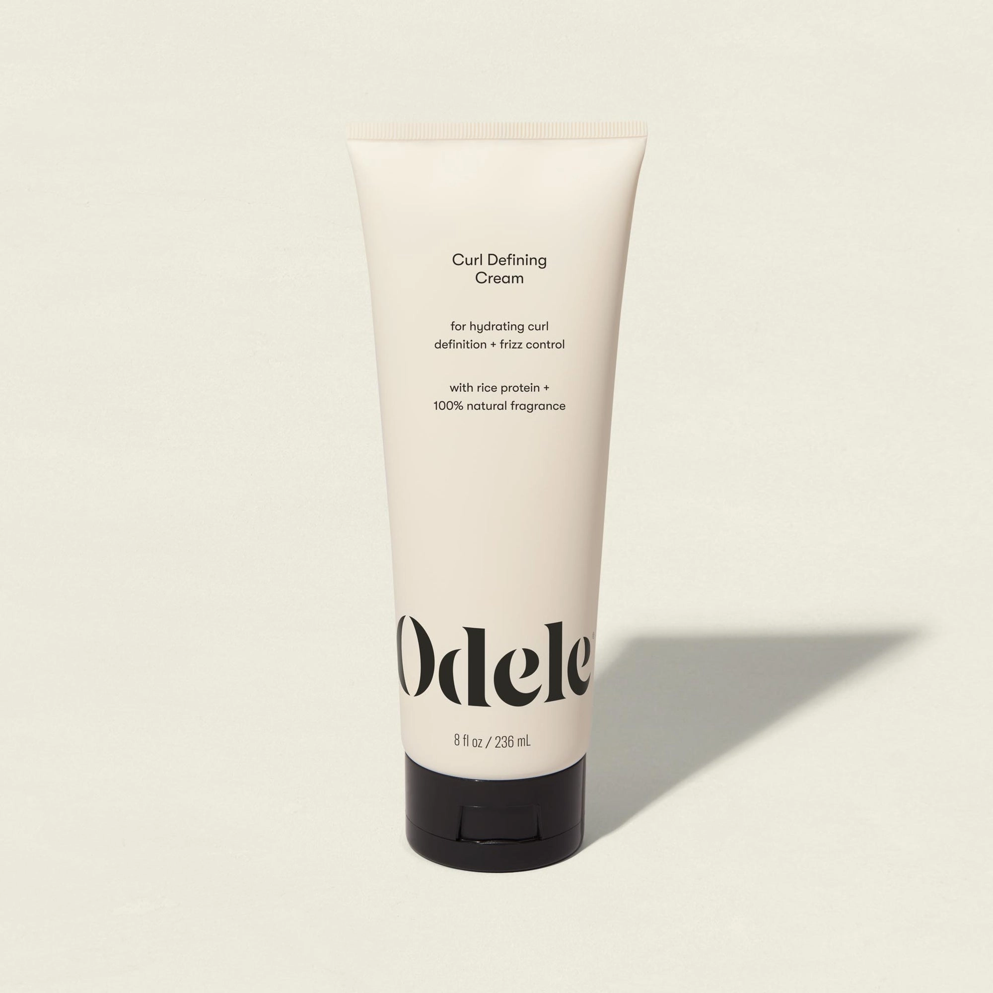 A beige tube of Odele Curl Defining Cream standing upright on a light surface