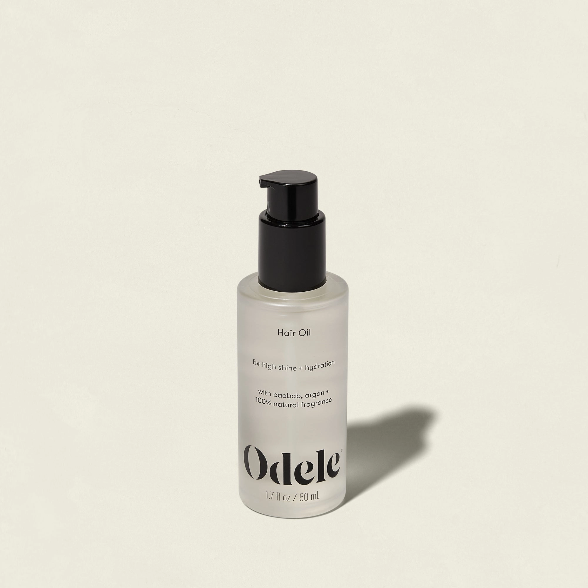 A clear bottle of Odele Hair Oil with a black pump dispenser on a neutral background