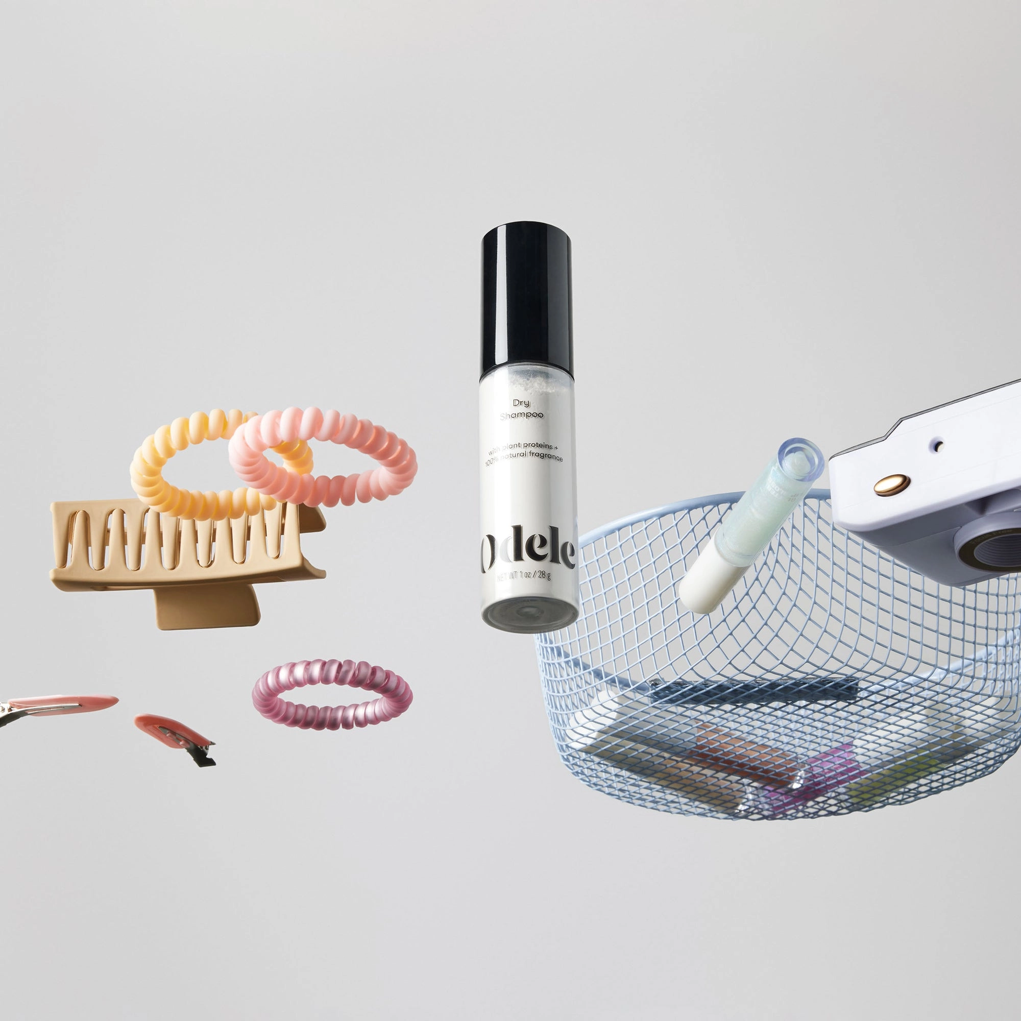 The Odele Dry Shampoo sits among assorted hair accessories on a clear surface